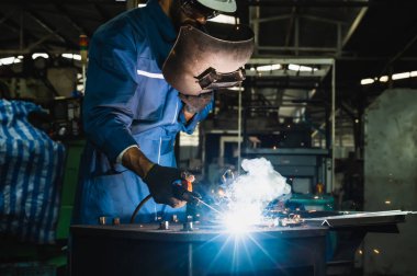 Metal kaynak yapan endüstriyel işçiler. Keskin kıvılcımları var.