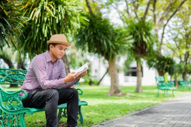 Asyalı genç bir adam kitap okuyor..