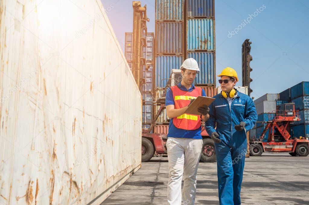 Foreman and dock worker staff working checking at Container cargo harbor holding clipboard. Business Logistics import export shipping concept.