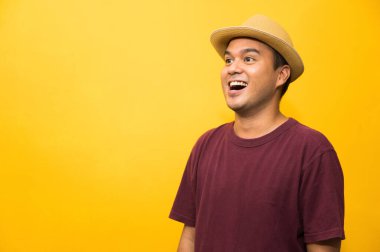 Genç Asyalı adam sarı arkaplanda boş boşluğa bakıyor..