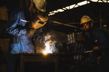 Metal kaynak yapan endüstriyel işçiler. Keskin kıvılcımları var.