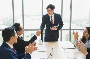 Asyalı iş adamları başarılı olmak için el sıkışıyor. İş adamlarından oluşan bir ekip el sıkışıyor, toplantıyı ofiste bitiriyor..