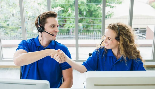 Customer support operator at work. Team Business and Delivery call center shaking hands in office. Working with a headset in blue uniform.