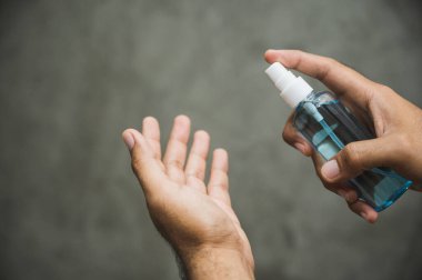 Yakın çekim erkek eli, plastik şişe spreyini alkol jeliyle itiyor. Coronavirus veya covid 19 konsepti.