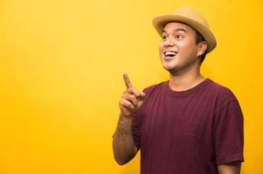 Genç Asyalı adam sarı arkaplanda boş boşluğa bakıyor..