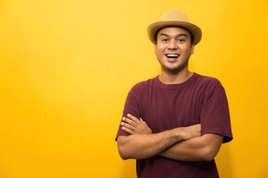 Sarı arka planda kolları çapraz olan yakışıklı Asyalı bir adam..