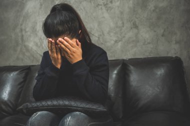 Bunalımlı Asyalı kadın, karanlık odada el ele oturuyor depresif, yalnız, dramatik ve üzgün..