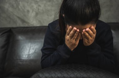 Bunalımlı Asyalı kadın, karanlık odada el ele oturuyor depresif, yalnız, dramatik ve üzgün..