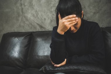 Bunalımlı Asyalı kadın, karanlık odada el ele oturuyor depresif, yalnız, dramatik ve üzgün..