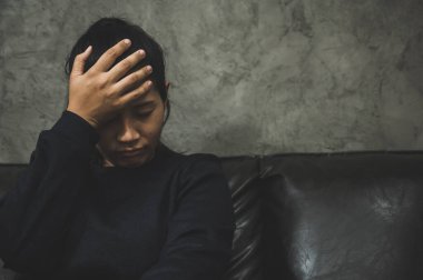 Bunalımlı Asyalı kadın, karanlık odada el ele oturuyor depresif, yalnız, dramatik ve üzgün..