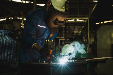 Metal kaynak yapan endüstriyel işçiler. Keskin kıvılcımları var.