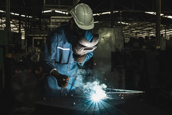 Industrial worker welding metal with many sharp sparks