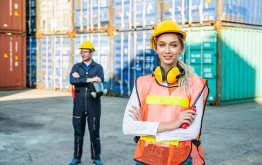 Konteyner kargo limanında çalışan iki işçi ve kadın işçi konteynırları yüklemeye çalışıyor. Rıhtım erkeği ve kadın personel lojistik ihracat nakliyat konsepti.