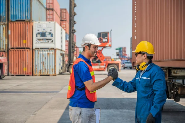 Foreman and dock worker staff shaking hand for sucess working at Container cargo harbor. Business Logistics import export shipping concept.