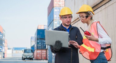 Konteyner kargo limanında dizüstü bilgisayarla çalışan ve konteynırları yüklemek için telsiz kullanan iki işçi ve kadın işçi. Rıhtım erkeği ve kadın personel lojistik ihracat nakliyat konsepti.