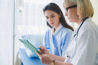 Kıdemli bayan doktor hastayla görüş ve semptom sorunu hakkında notlar alın. Tıp konseptinde sağlık ve müşteri hizmetleri.