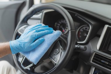 Adam mikrofiber bezle arabayı temizliyor.