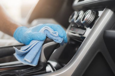 Adam mikrofiber bezle arabayı temizliyor.