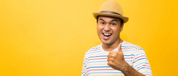 戴帽子的年轻亚洲人感到快乐和惊奇 并在黄色背景上露出大拇指 — 图库照片