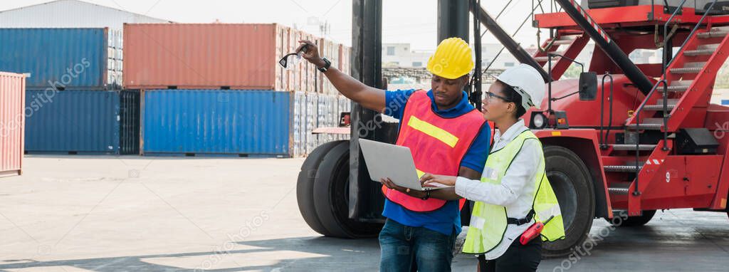 Two Black foreman man & woman worker working checking at Container cargo harbor holding laptop computer and using walkie-talkie to loading containers. African dock male and female staff business Logistics import export shipping concept.