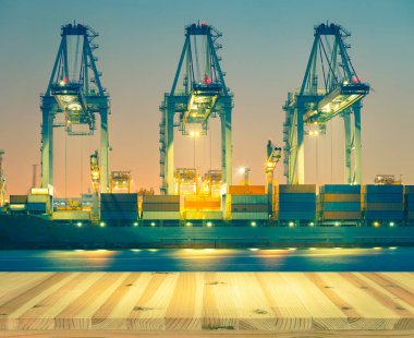 Kargo gemisi alacakaranlık vakti limanda konteynır boşaltıyor..