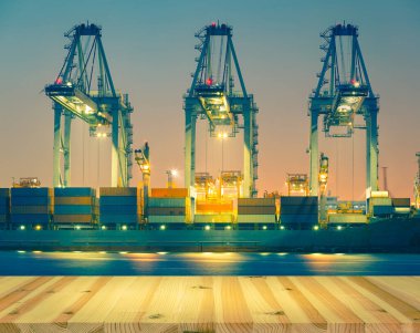 Kargo gemisi alacakaranlık vakti limanda konteynır boşaltıyor..