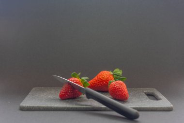 Çilek kesmek. Bir bıçak gözleniyor ve kesme tahtasının üzerinde çilekler kesiliyor..