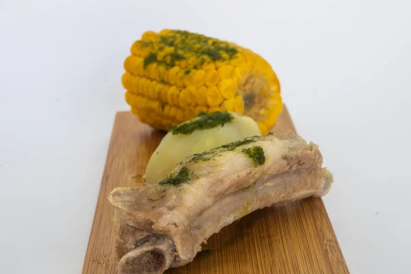 Potatoes, corn and ribs, a typical dish from the island of Tenerife. The potatoes, corn and ribs are accompanied by a green mojo. The green mojo is coriander. Tipical from canary islands.