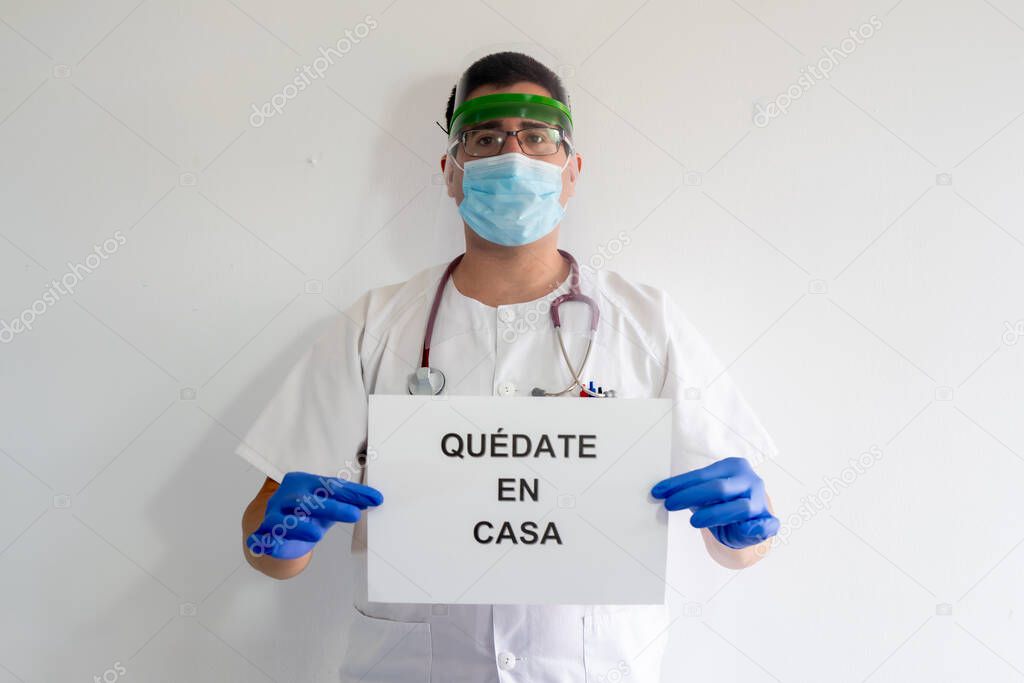 A male nurse with a face protector, mask, gloves and stethoscope. He has a sign that says 