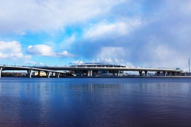 Stadyum, nehir köprüsü ve parlak gökyüzü