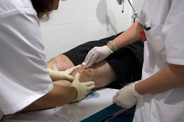 Enfermeras con guantes curan herida on rodilla 