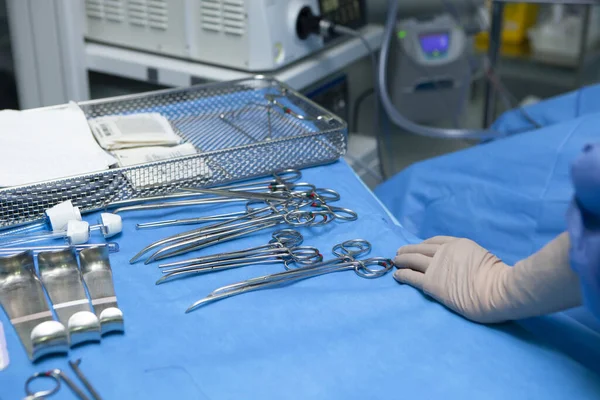 Mano de enfermera con material de quirofano como tijeras