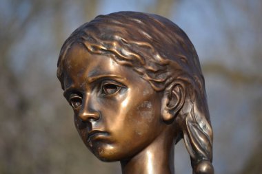 Kızın kafası, yarı-profil. Üzgün, sıska, aç kız. Bronz heykel. Wascana Parkı, Regina, Saskatchewan, Kanada. 1932 'de kıtlık sırasında ölen Ukraynalıların ve Kazakların anısına..
