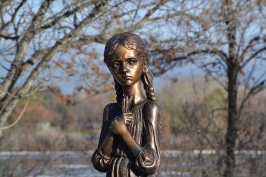 Elinde buğday tutan sıska üzgün kız. Bronz halka açık heykel. Wascana Parkı, Regina, Saskatchewan, Kanada. 1932 'de kıtlık sırasında ölen Ukraynalıların ve Kazakların anısına..