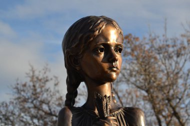 Elinde buğday tutan sıska üzgün kız. Bronz halka açık heykel. Wascana Parkı, Regina, Saskatchewan, Kanada. 1932-33 yıllarında kıtlık sırasında ölen Ukraynalıların ve Kazakların anısına..