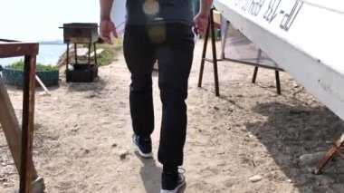 Adam deniz kenarında, kumsalda antrenman yapıyor, denize ve kuma bakıyor, boks yapıyor, koşuyor, telefonda konuşuyor, deniz taşı fırlatıyor.