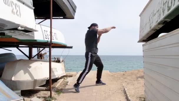 남자는 바다와 해변에서 훈련을 있습니다 바다와 모래를 내려다 돌멩이던지기 — 비디오