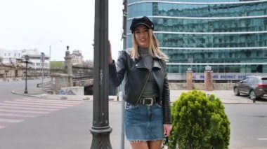 Fransız tarzı bir Fransız kadın, şehir merkezinde küçük bir etekle yürüyor, elinde bir çanta, ayakkabılarını düzeltmek için eğiliyor, sokak lambalarının etrafında dönüyor, gülümsüyor.