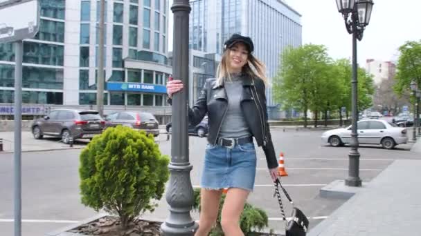 フランス風の女の子が街の中心部を歩き回り ミニスカートの中をハンドバッグで歩き 靴をまっすぐに曲げ ランプポストの周りを旋回し — ストック動画