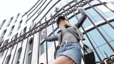 Fransız tarzı bir Fransız kadın, şehir merkezinde küçük bir etekle yürüyor, elinde bir çanta, ayakkabılarını düzeltmek için eğiliyor, sokak lambalarının etrafında dönüyor, gülümsüyor.