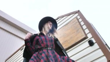 Limanda, yatların yanında poz veren kız, kısa bir elbise, yuvarlak bir şapka ve yüksek çizmelerle yürüyor, gülümsüyor.