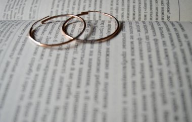 Genişletilmiş bir kitabın üzerinde iki altın küpe var.