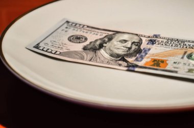 Tabakta para var. Kırmızı arka plan. Dolar tabakta yatıyor.