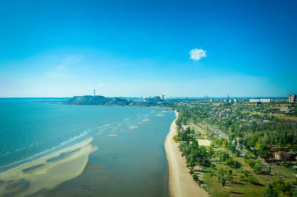 Yazın sanayi şehri. Ufukta deniz kenarında metalürjik bir bitki var.