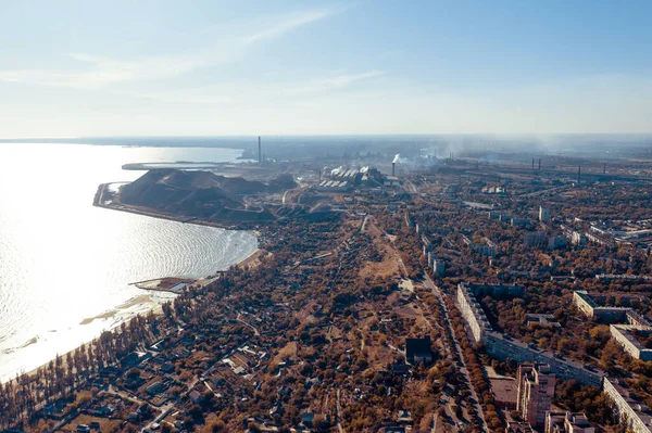 Yazın sanayi şehri. Ufukta deniz kenarında metalürjik bir bitki var.