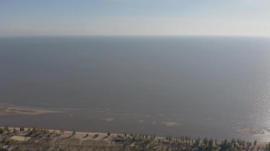 Sanayi şehrinde günbatımı. Ufukta deniz kenarında metalürjik bir bitki var.