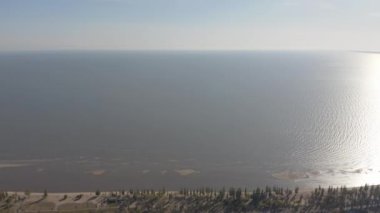 Sanayi şehrinde günbatımı. Ufukta deniz kenarında metalürjik bir bitki var.