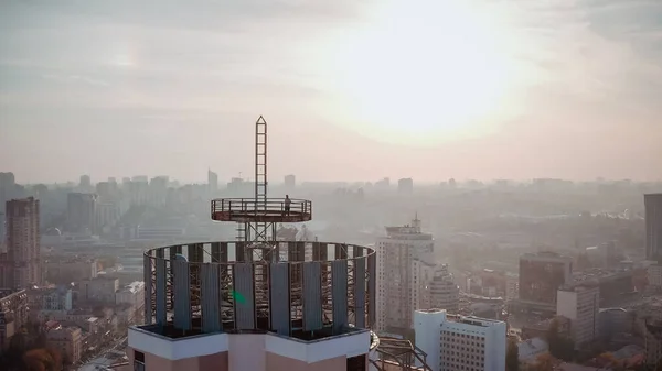 Bir gökdelenin çatısında cesur bir adamın silueti. 