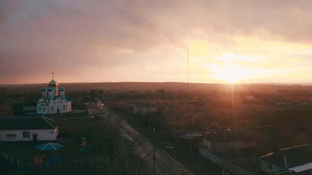 Kostel v malém městě. epický západ slunce a plynulý pohyb kamery - Letecký pohled — Stock video
