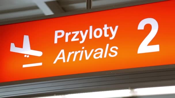 Poste de señal del aeropuerto en polaco e inglés. Tablero informativo naranja. llegadas — Vídeo de stock